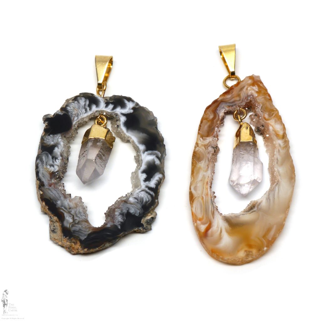 Agate geode slice pendants with quartz crystals linked in the middle featuring gold plated bails against a white background