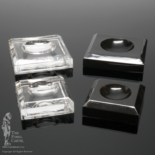 Clear and black square dimple block acrylic stands against a black background