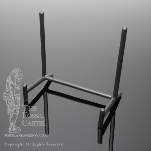 A low profile display stand of black wrought iron, meant to hold a slab upright but low off of the surface it sits on.