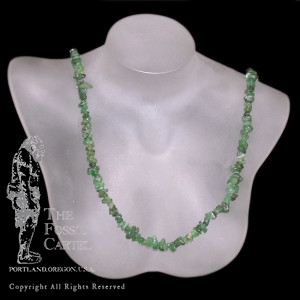 A tumbled emerald chip necklace against a black background