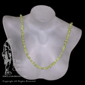 A tumbled peridot chip necklace against a black background