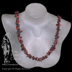 A tumbled red tiger's eye chip necklace against a black background