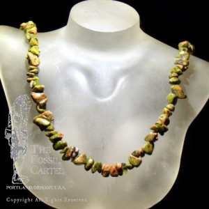 A tumbled unakite chip necklace against a black background