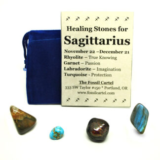 A sagittarius healing pouch containing a tumbled rhyolite stone, turquoise, red garnet, and a labradorite tumbled stone along with a blue felt pouch, against a white background