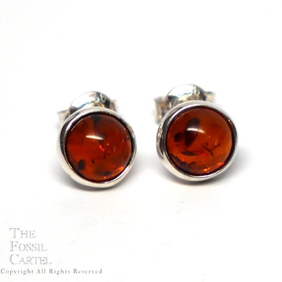 A pair of simple round sterling silver stud earrings with amber cabochons against a white background