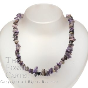 A necklace made of tumbled charoite chips against a white background