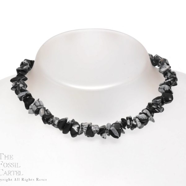 A stone chip necklace made of snowflake obsidian against a grey background