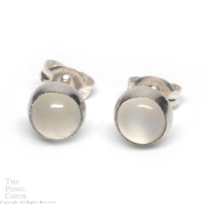 A pair of simple round sterling silver stud earrings featuring round colorless moonstone cabochons against a white background