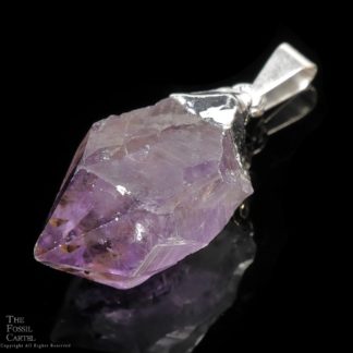 An amethyst crystal point pendant capped in base metal against a black background