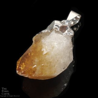 A treated citrine crystal point pendant capped in base metal against a black background