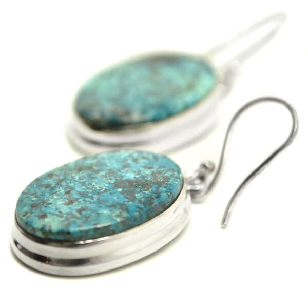 A pair of sterling silver dangle earrings featuring shattuckite cabochons against a white background