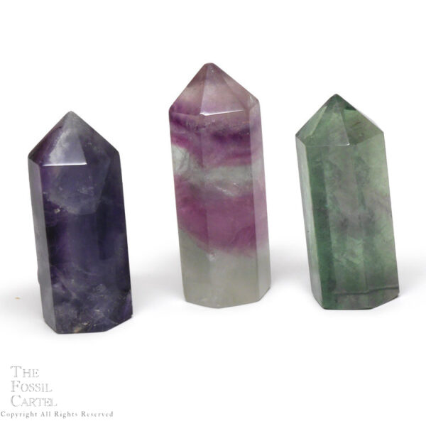 3 pieces of fluorite cut and polished into crystal points with a flat bottoms against a white background