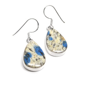 A pair of daingly sterling silver earrings set with teardrop K2 granite cabochons against a white background