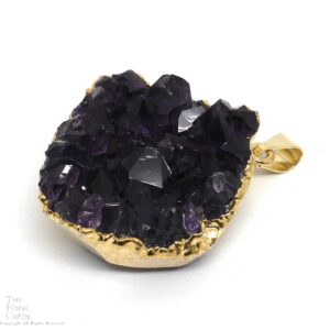 A small cluster of dark purple amethyst crystals with gold-colored electroplating affixed to a bail which it hangs from to be worn as a pendant