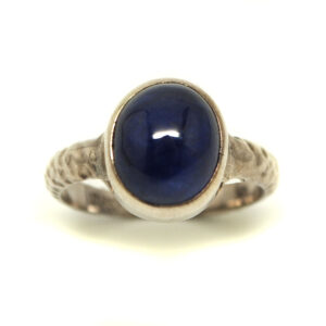 Translucent Sapphire cabochon set in sterling silver ring with hammered style band against a white background