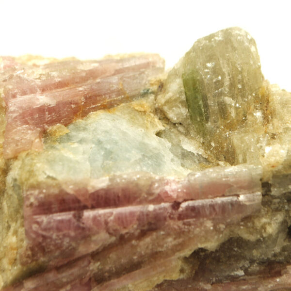 Rubellite (pink tourmaline) crystals with aquamarine inclusions in quartz matrix against white background