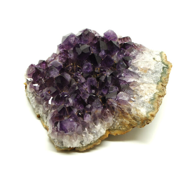 A side view of a purple amethyst crystal cluster with agate banding along the edges of the cluster against a white background