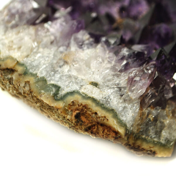A purple amethyst crystal cluster with agate banding along the edges against a white background