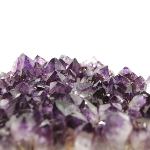 A purple amethyst crystal cluster against a white background