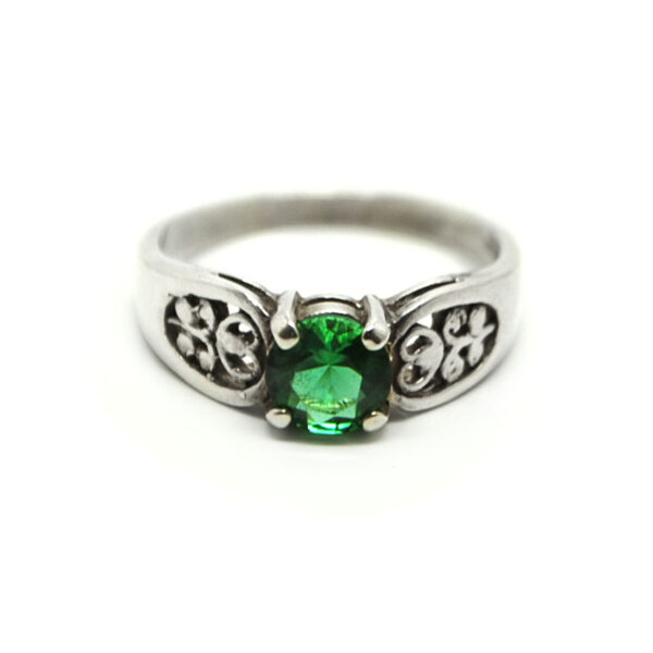 A round faceted emerald obsidianite gemstone prong-set into a filigree sterling silver ring against a white background