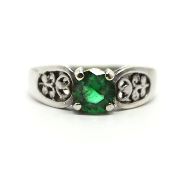 A round faceted emerald obsidianite gemstone prong-set into a filigree sterling silver ring against a white background