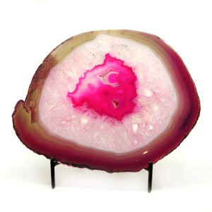 An agate slice that has been dyed pink with definitive banding along the edges set against a white background