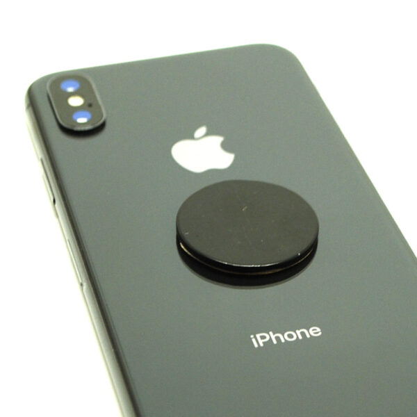 A circular shungite phone tile sticker on a grey smart phone against a white background