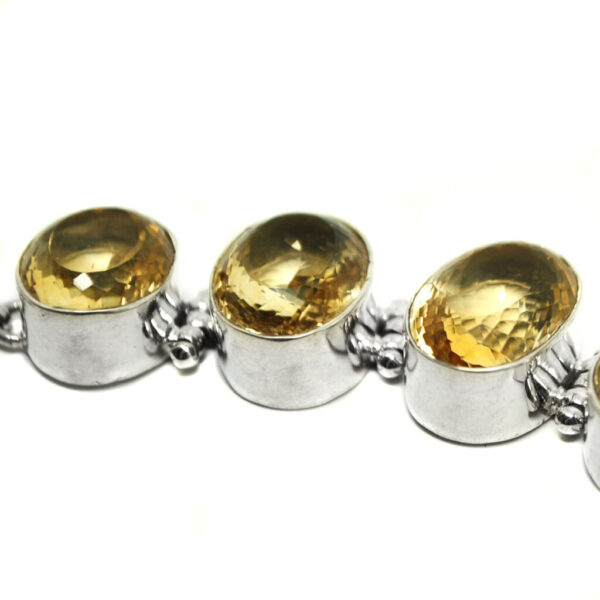 A chunky, oval-faceted citrine sterling silver bracelet against a white background