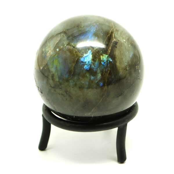 A colorful polished labradorite sphere in a circular iron stand against a white background