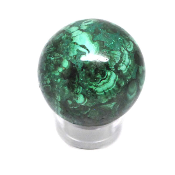 A piece of malachite carved and polished into a sphere against a white background