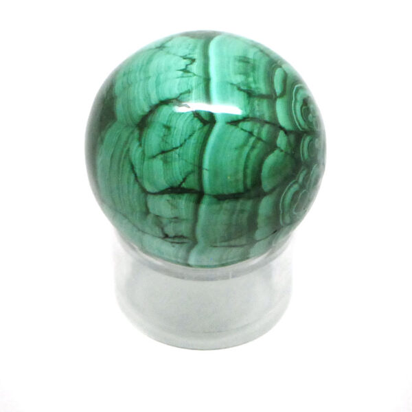 A piece of malachite carved and polished into a sphere against a white background