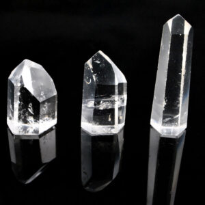 Three clear quartz crystal polished points against a black background