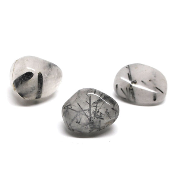 A set of 3 tumbled tourmalinated quartz stones against a white background