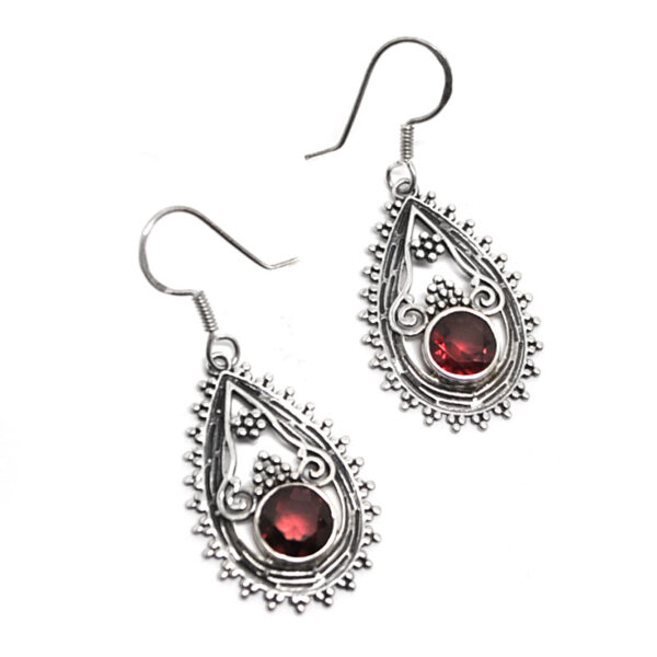 A pair of ornate sterling silver earrings with faceted garnet gemstones against a white background