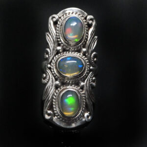 An ornate sterling silver ring featuring 3 oval ethiopian opals with rainbow play of color against a black background