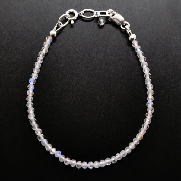 A rainbow moonstone microbead bracelet with a sterling silver lobster claw clasp against a black background