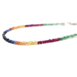 A ruby, emerald, and sapphire microbead bracelet with a sterling silver lobster claw clasp against a white background
