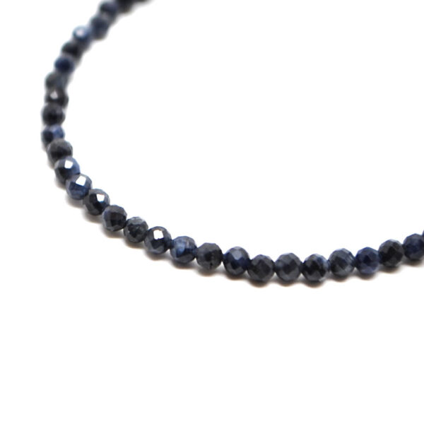 A dark blue sapphire microbead bracelet with a sterling silver lobster claw clasp against a white background