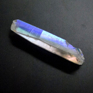 A platinum vapor treated iridescent quartz crystal against a black background