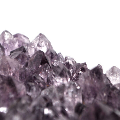 A deep purple amethyst crystal cluster from Uruguay against a white background