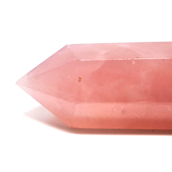 A piece of pink rose quartz that has been cut and polished into a tower against a white background