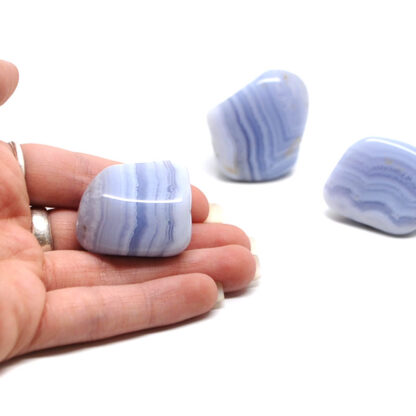 A set of three blue lace agate tumbled stones against a white background