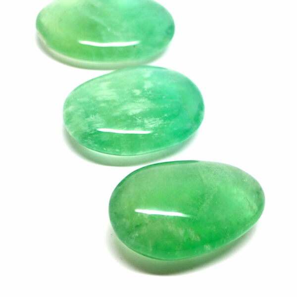Three vibrant green fluorite palm stones against a white background