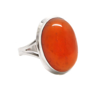 A vibrant oval carnelian cabochon set into a sterling silver ring against a white background