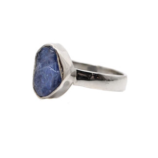 A simple sterling silver ring set with a rough tanzanite gemstone against a white background
