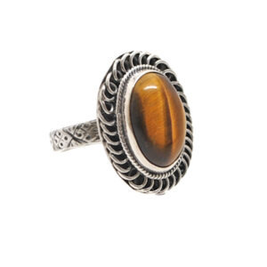 An oval tiger's eye cabochon set into a decorative sterling silver ring with a textured band and roped bezel against a white background