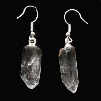 A pair of clear quartz crystal earrings with simple ear hooks against a black background