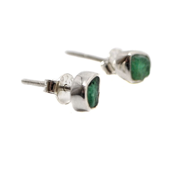 A pair of sterling silver stud earrings set with rough emerald gemstones against a white background