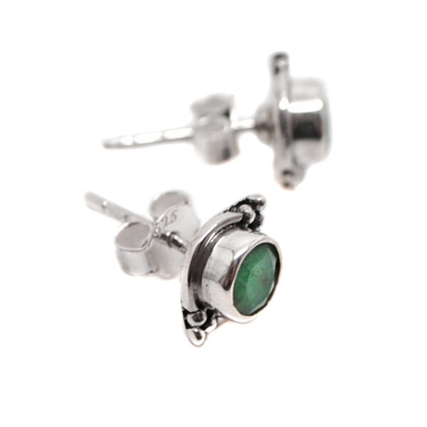 A pair of sterling silver stud earrings set with round faceted emerald gemstones against a white background