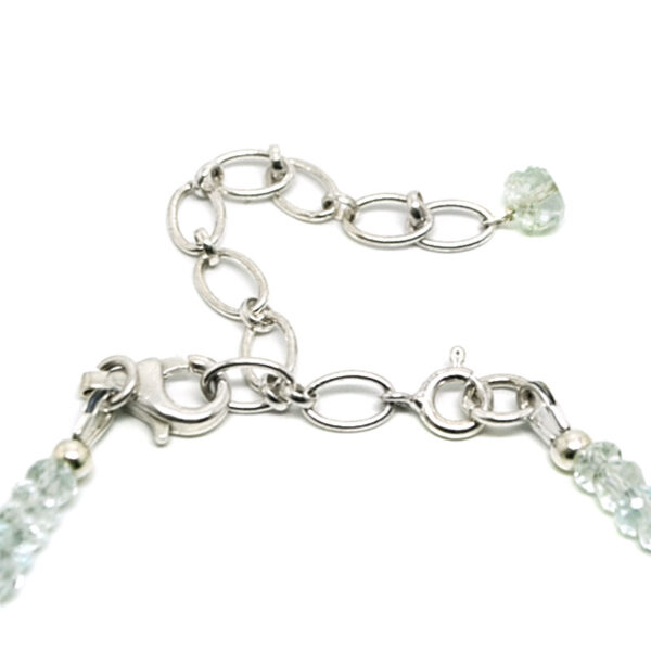 A beaded necklace featuring faceted aquamarine with a sterling silver lobster claw clasp against a white background